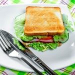 Toast with fried bread, ham and vegetables on a white plate with